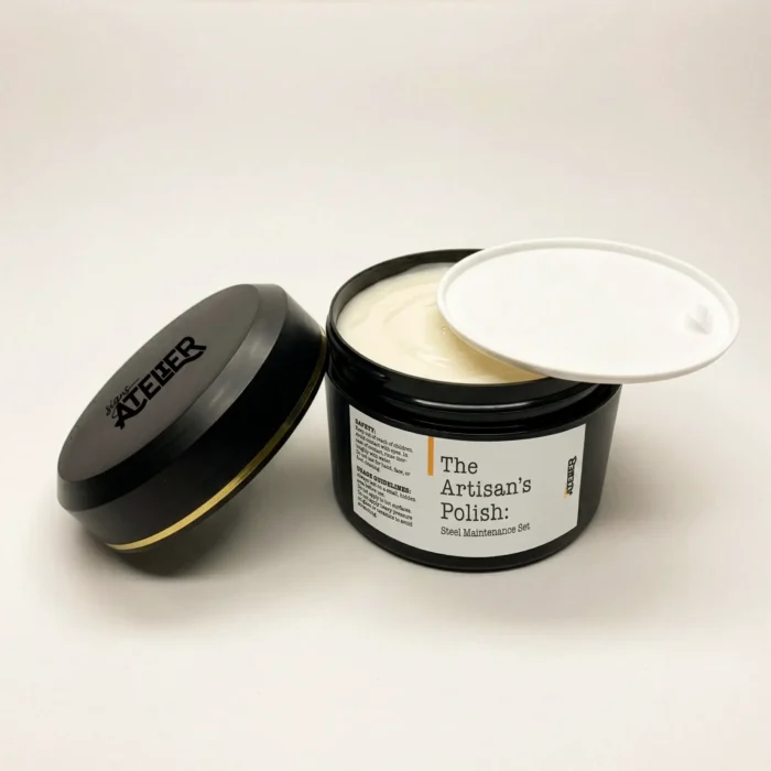 A clear, black jar containing white polishing cream. The jar has a label that reads 'The Artisan's Polish: Steel Maintenance Set', a white inner lid around the edge, and a black outer lid with a gold stripe and the 'signs ATELIER' logo.