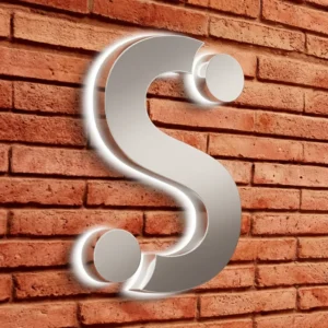 Silver metallic reverse channel letters in the shape of the letter S with white LED halo lighting on a red brick wall.